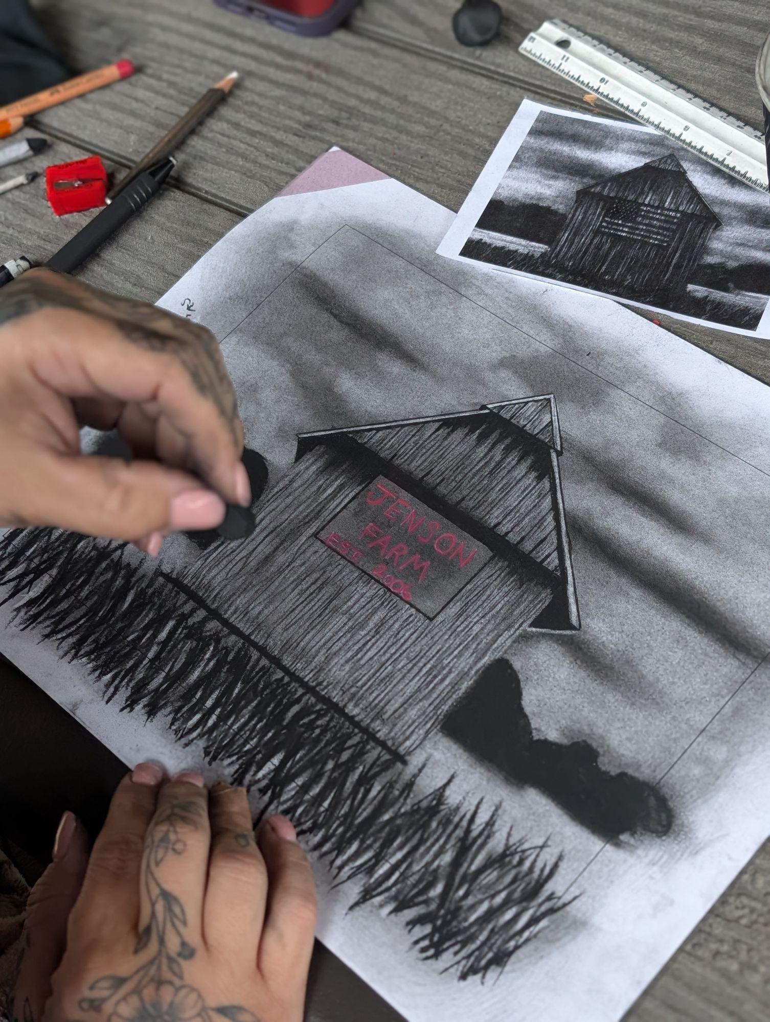 Charcoal drawing in progress with tools and reference sketches nearby