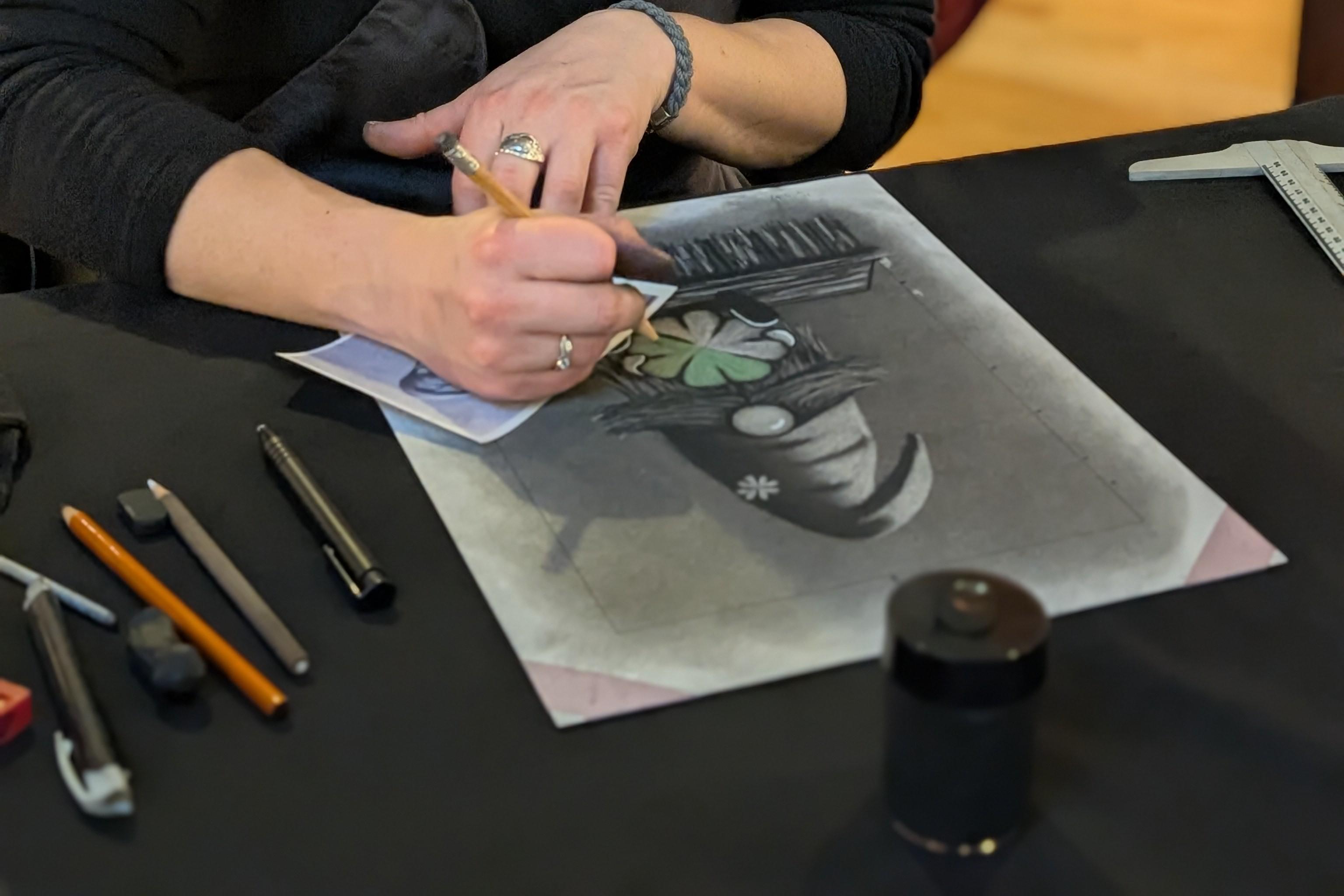 Hands creating a charcoal drawing with supplies at a live event